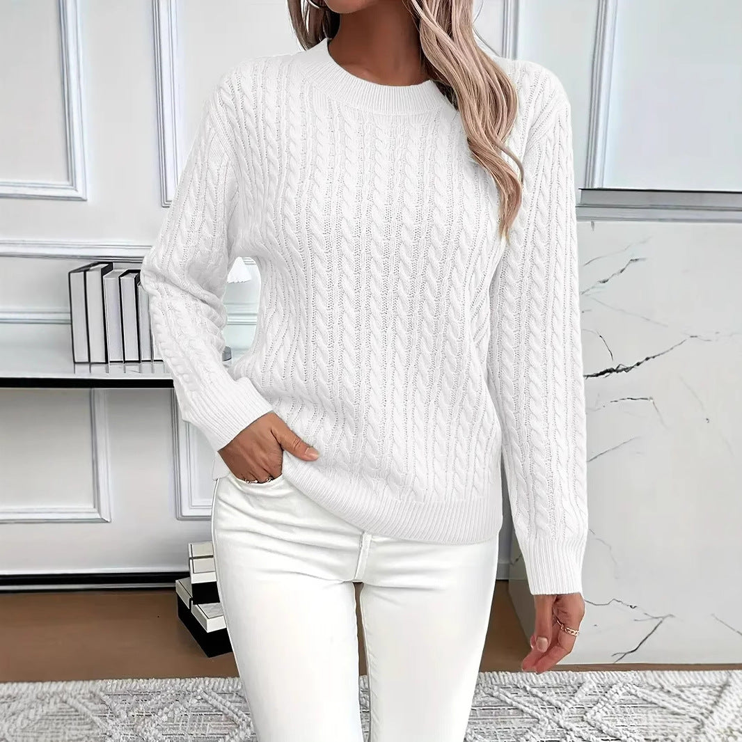 Person wearing a white cable knit sweater and white pants in a room with a marble floor.