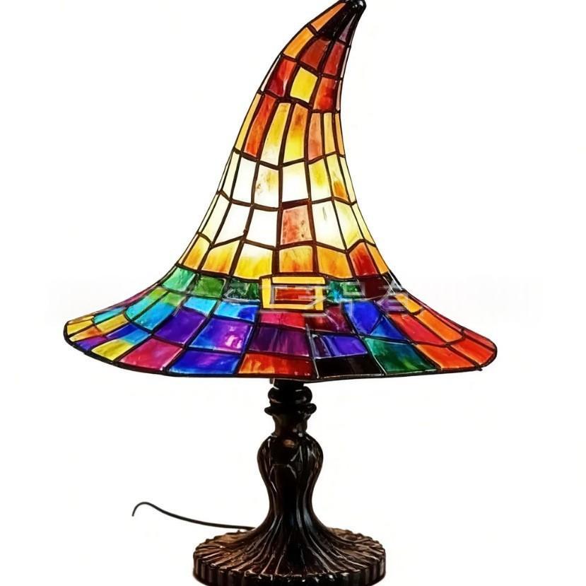 A stained glass table lamp shaped like a witch's hat, featuring a vibrant multicolor glass shade with yellow, orange, red, green, blue, and purple panels, mounted on a dark brown metal base.