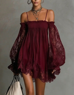Woman wearing a burgundy off-shoulder dress with sheer sleeves against a gray background