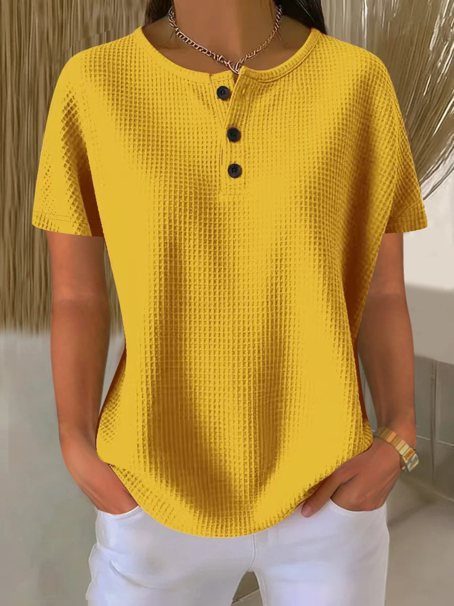 Yellow textured shirt with black buttons worn by a person, against a neutral background