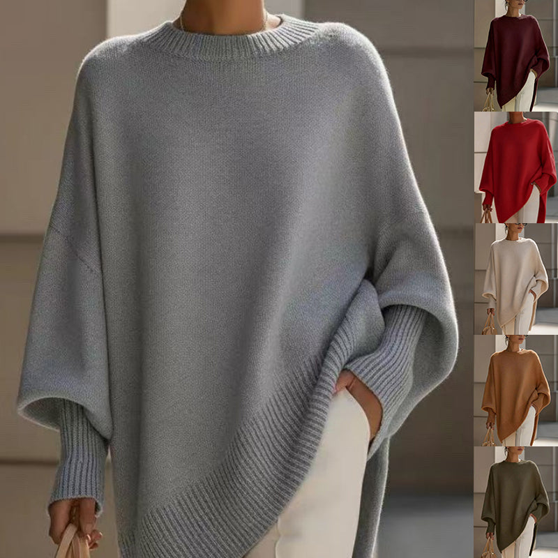A woman wears an oversized light gray knit sweater with wide batwing sleeves and ribbed cuffs and hem. A vertical strip on the right shows the same sweater in additional colors: burgundy, red, cream, tan, and olive green.