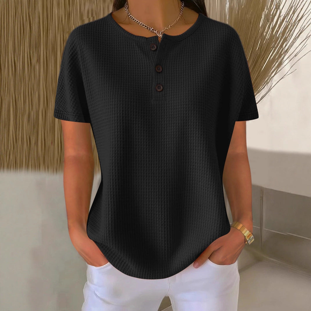 Person wearing a black textured shirt and white pants against a neutral background