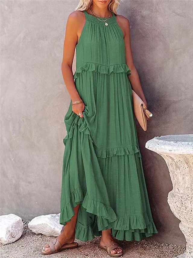 Woman wearing a green dress with ruffled layers against a neutral background.