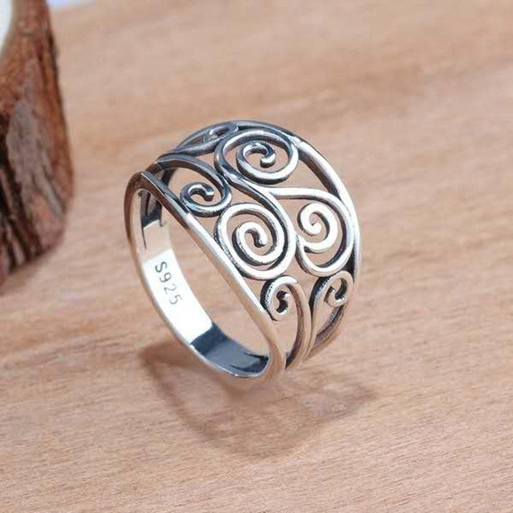 Silver ring with intricate design on a wooden surface