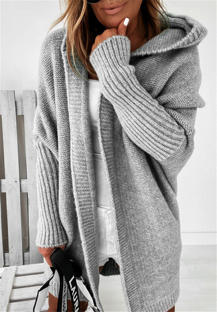 Person wearing a gray knitted cardigan with a white background
