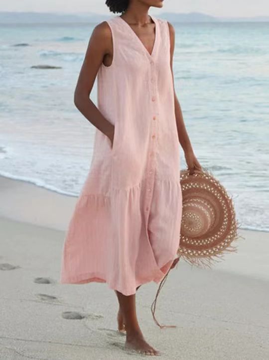 Woman in a pink dress holding a straw hat on a beach