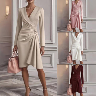 Woman wearing a beige dress with long sleeves in a room with a gray floor and white walls.