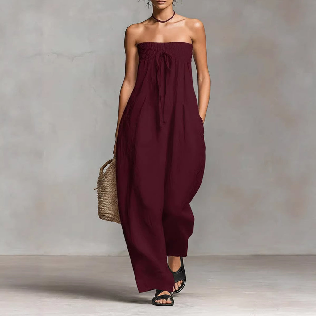 Woman wearing a strapless burgundy jumpsuit against a neutral background