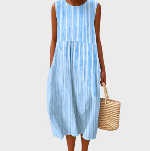 Woman wearing a light blue striped dress holding a woven bag on a plain background