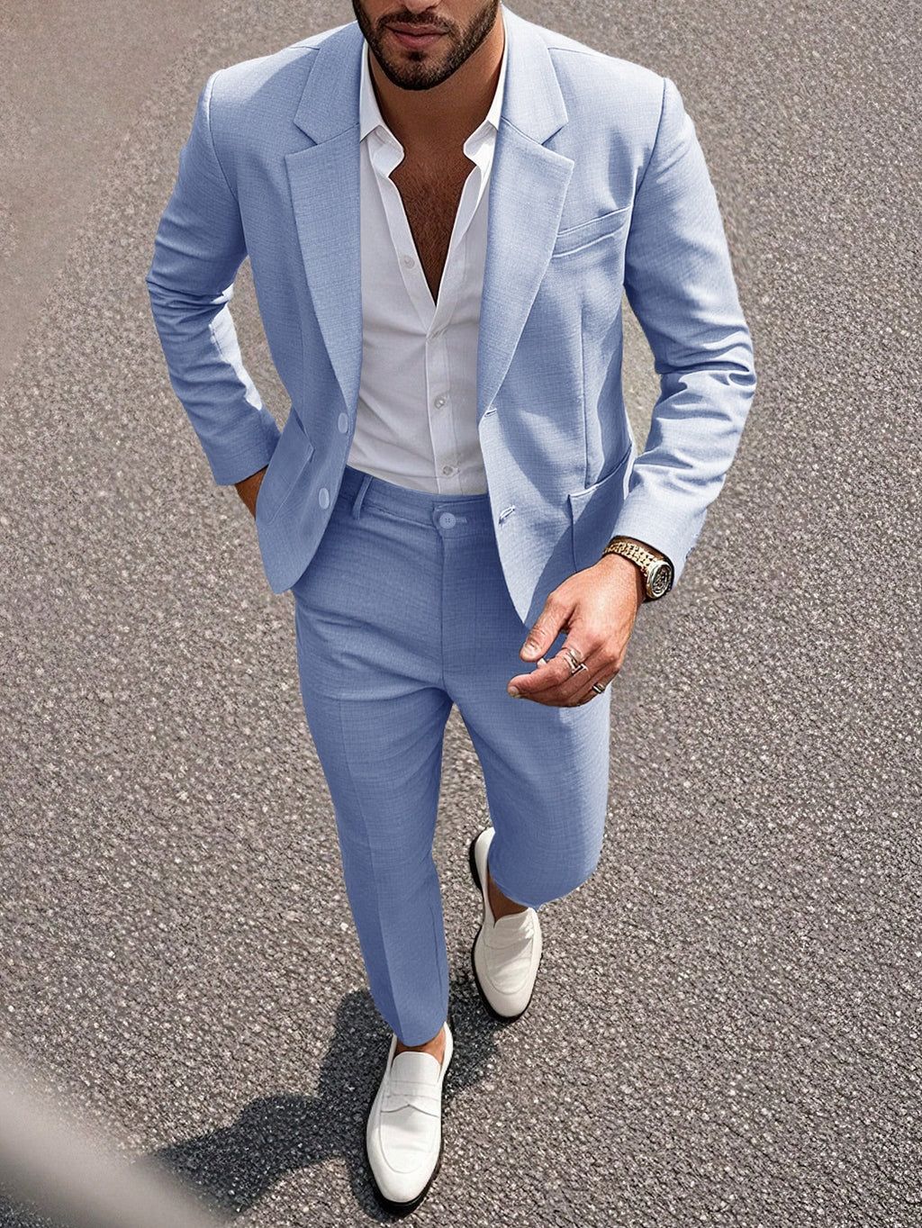 Man wearing a light blue suit with white shirt and shoes on a road.