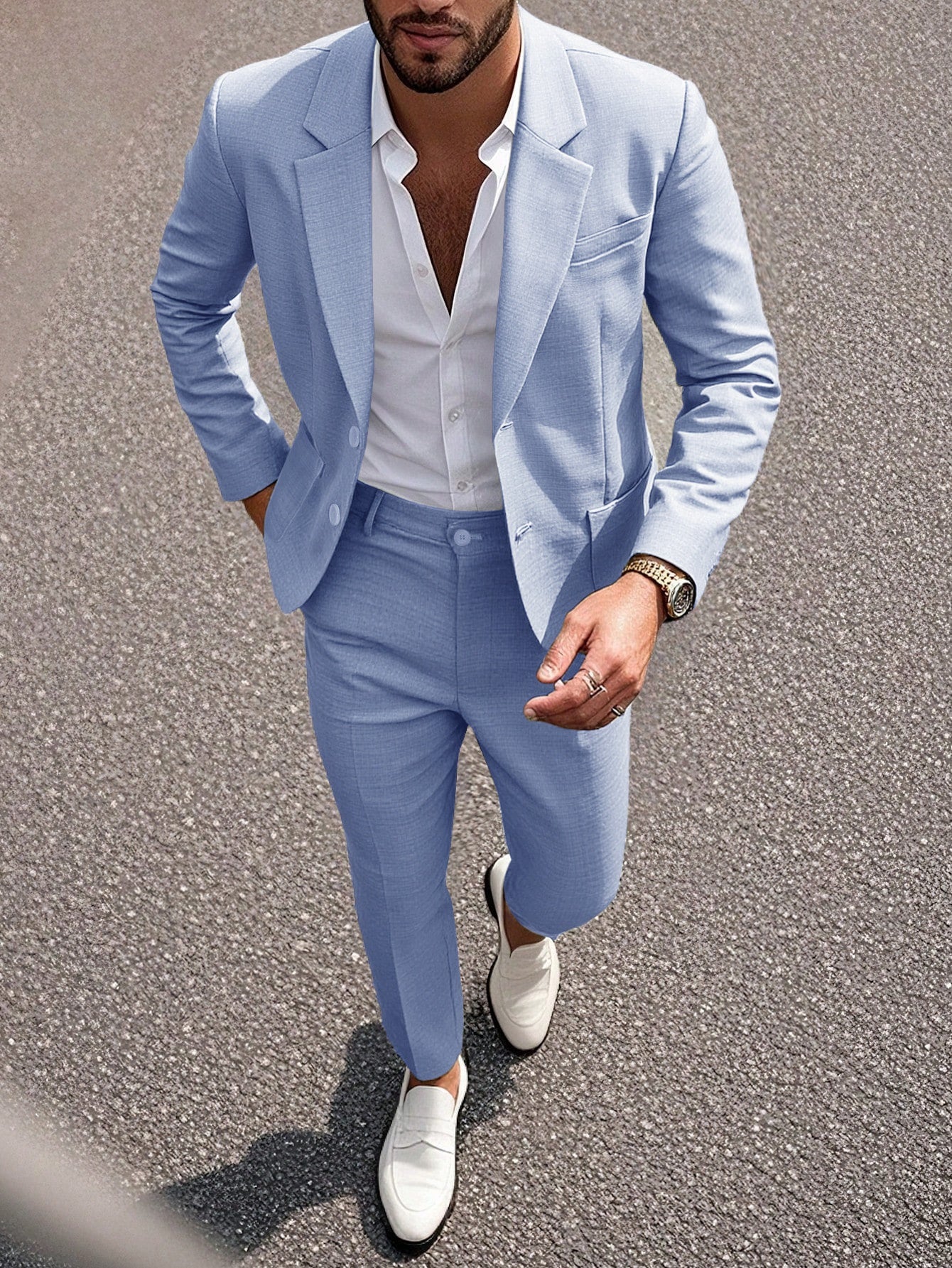 Man wearing a light blue suit with white shirt and shoes on a road.