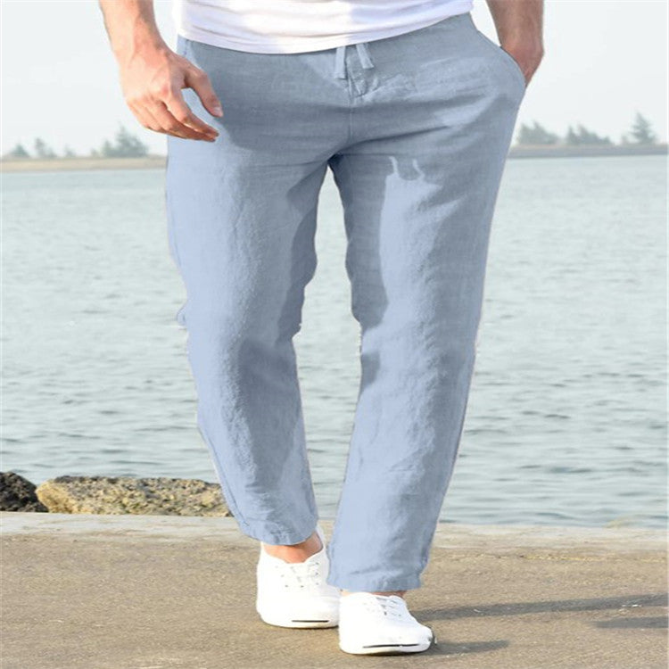 Person wearing light blue pants and white shoes by a body of water.