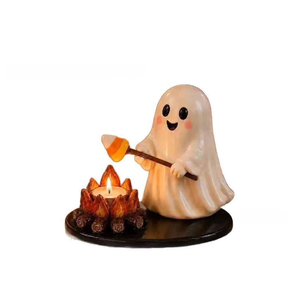 A cute ghost-shaped candle holder figurine roasting a marshmallow over a small campfire on a black base, set against a plain white background.