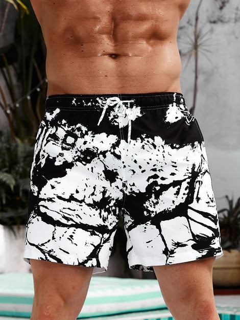 Person wearing black and white patterned swim shorts with a blurred background
