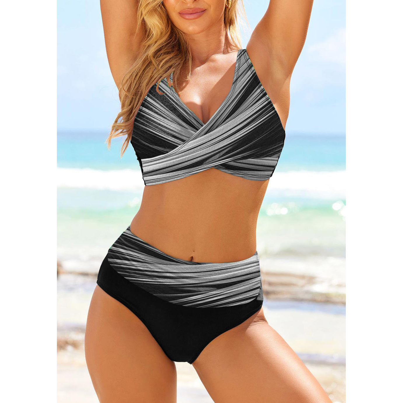Woman wearing a black and gray striped swimsuit on a beach.