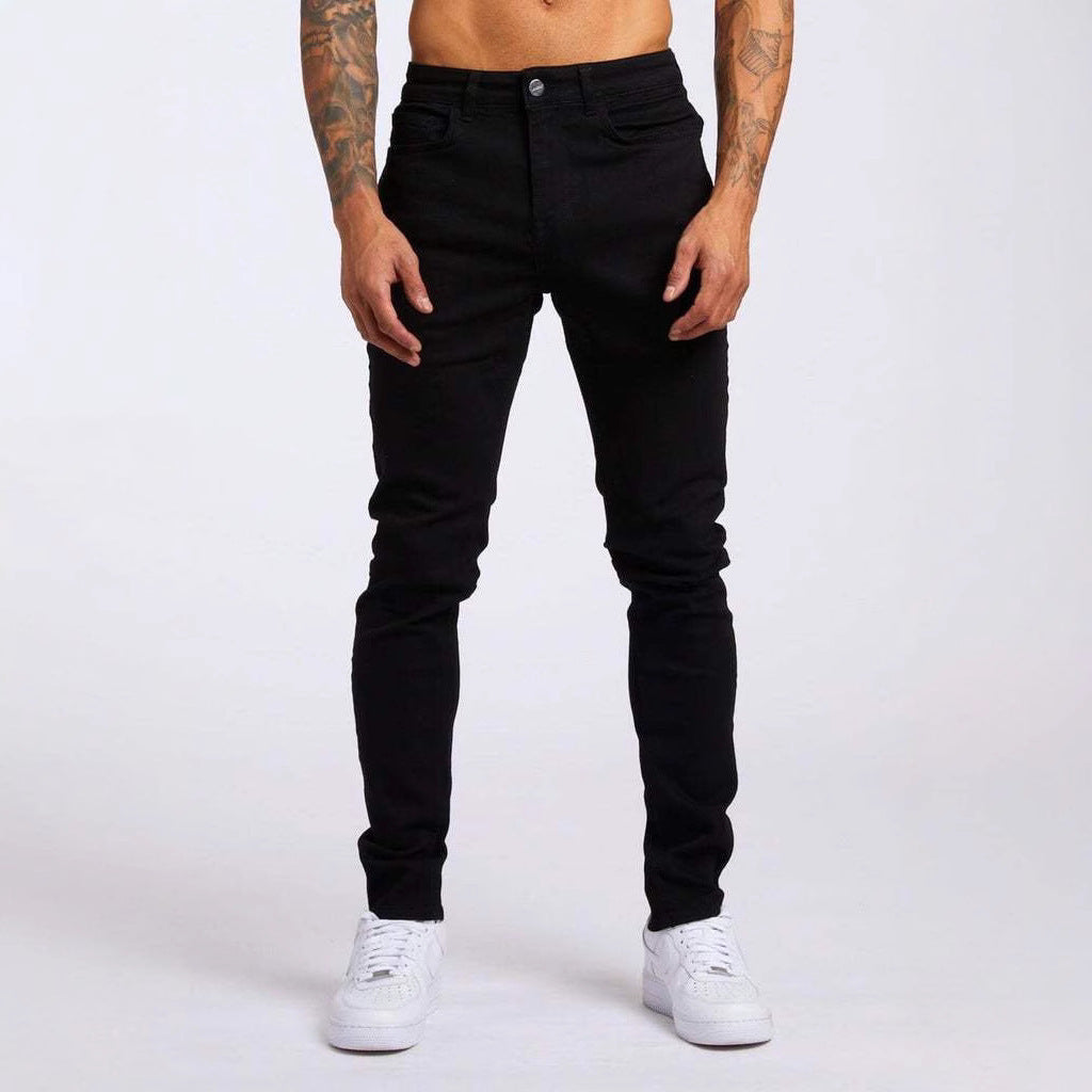 Person wearing black jeans and white sneakers on a plain background