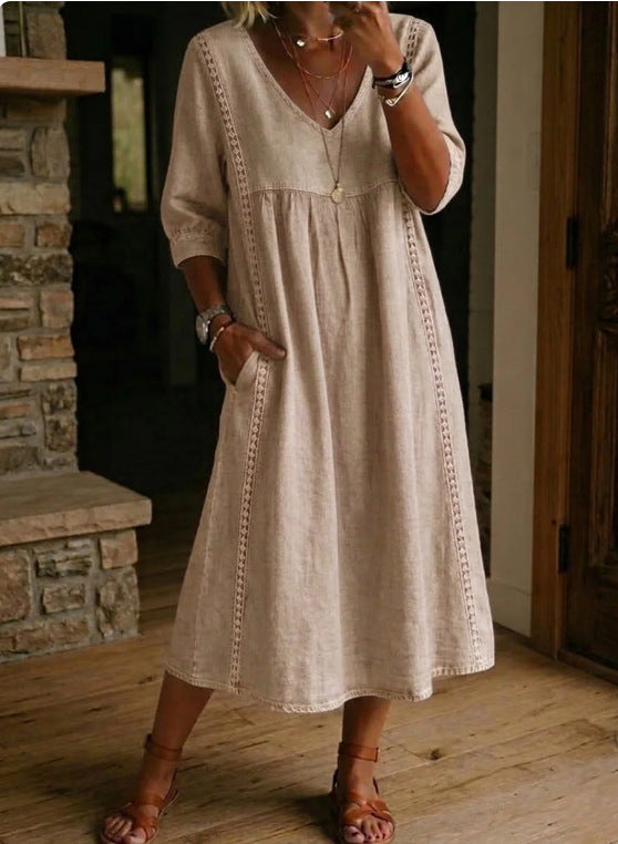 Woman wearing a beige dress with intricate patterns indoors.