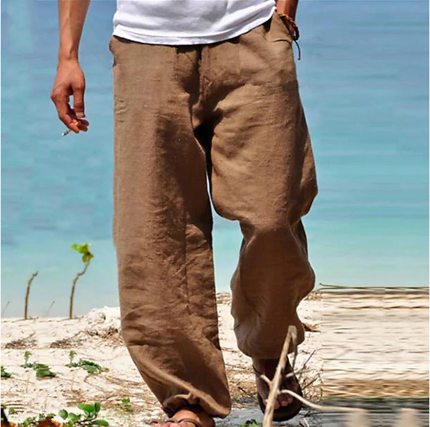 Person wearing brown pants standing on a beach with a clear blue sky.