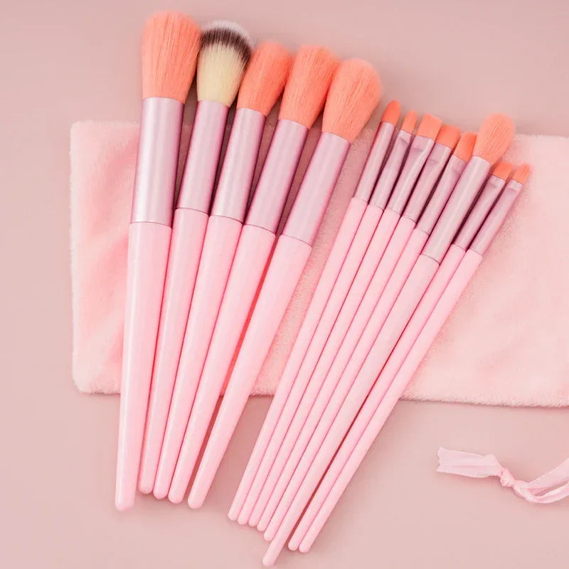 Set of pink makeup brushes with soft bristles and matching pouch on a pastel surface