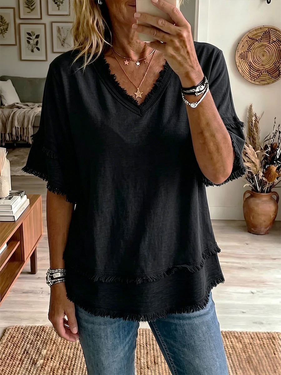 Person wearing a black top with ruffled sleeves in a living room setting.