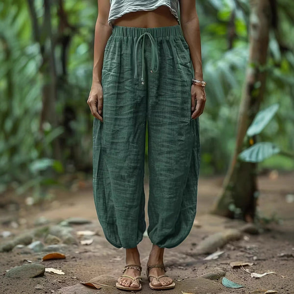Person wearing green harem pants standing in a natural setting with greenery.