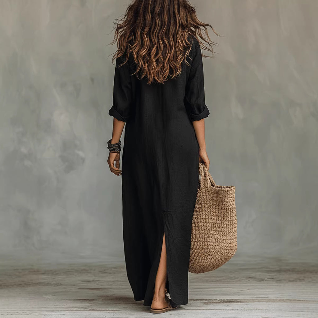 Person wearing a black dress holding a woven bag against a gray wall.