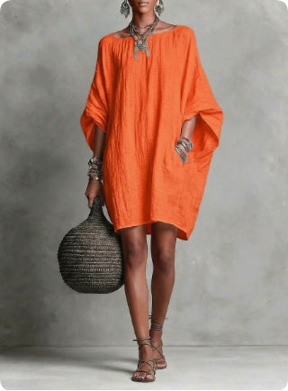 Woman wearing an orange dress holding a black bag against a gray background