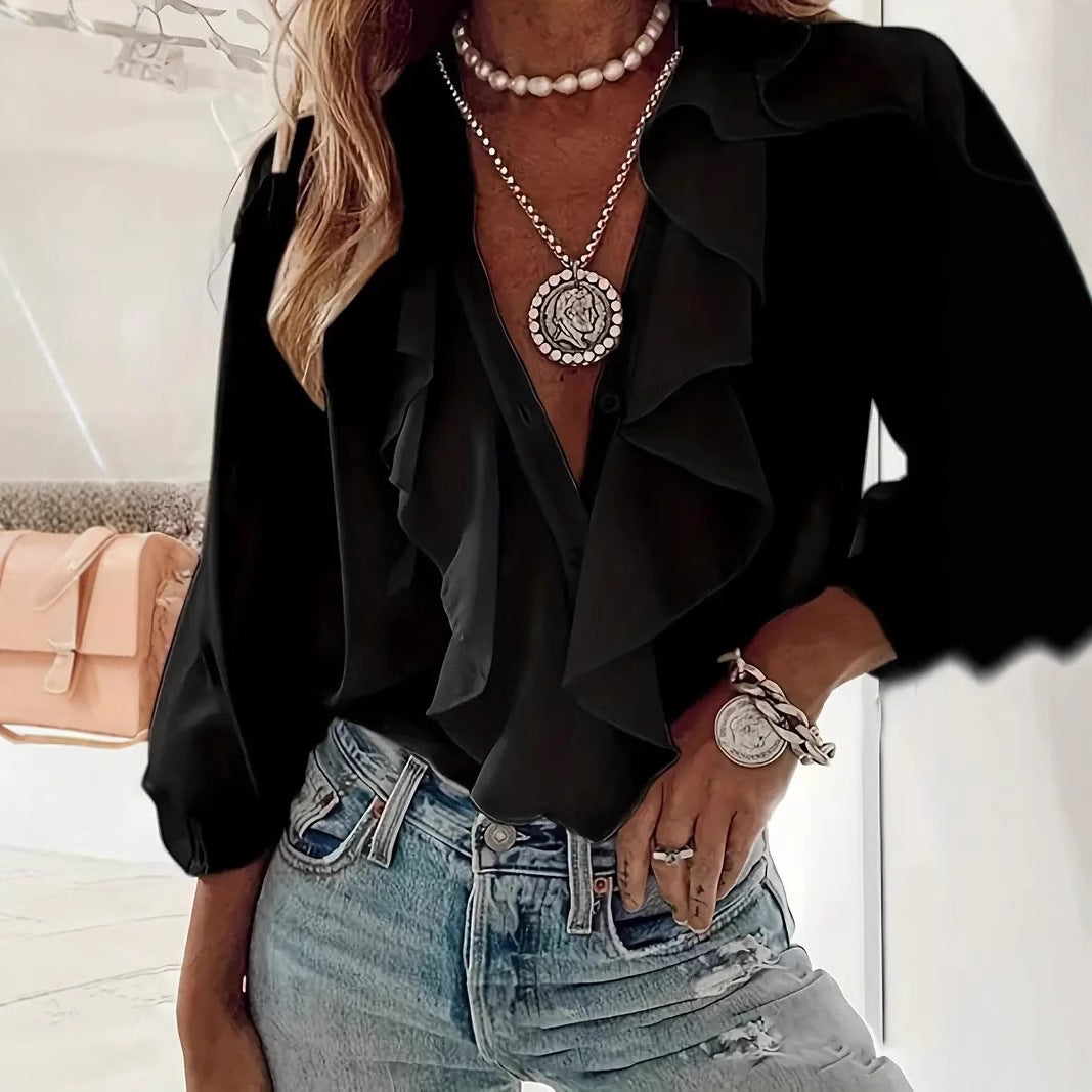 Person wearing a black ruffled blouse and blue jeans with jewelry.