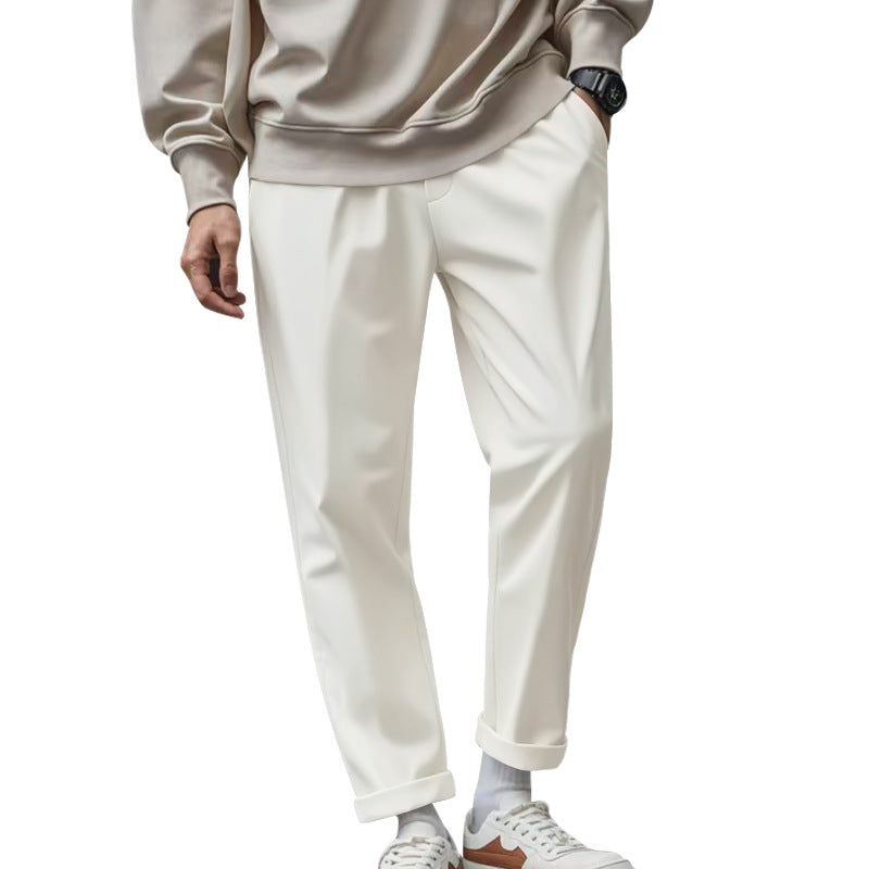 Person wearing a beige sweatshirt and white pants on a white background