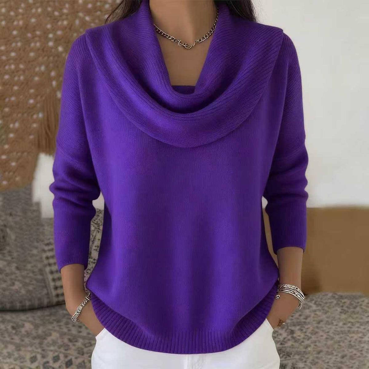 Person wearing a purple cowl-neck sweater with a neutral background