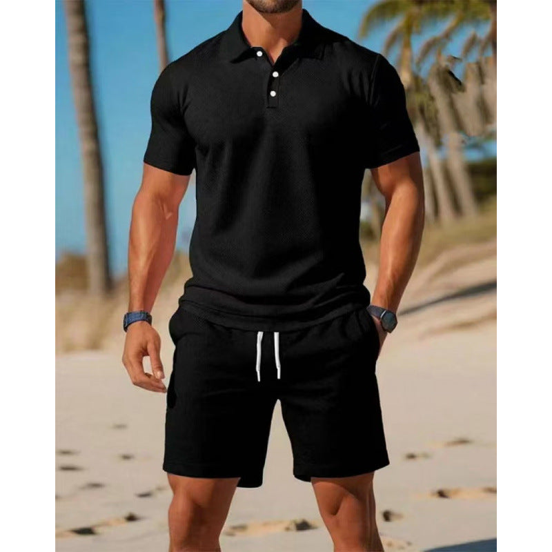 Man wearing a black polo shirt and shorts on a beach with palm trees in the background