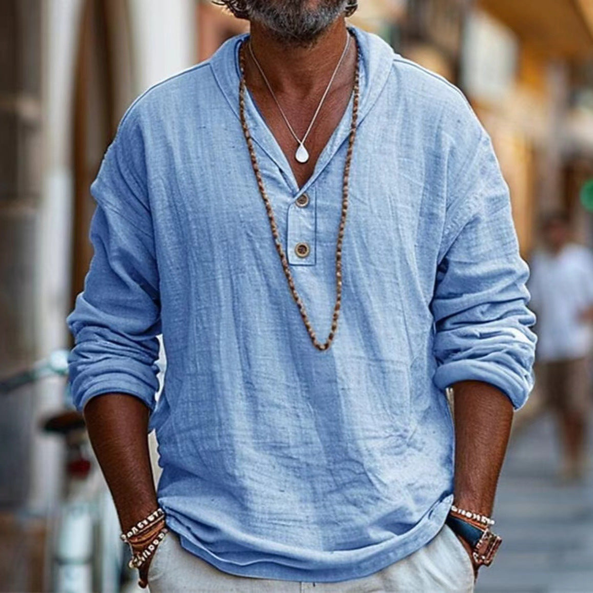 Man wearing a light blue long-sleeve shirt with a blurred street background
