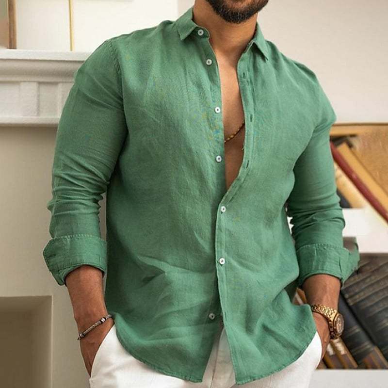 Man wearing a green button-up shirt with rolled-up sleeves indoors.