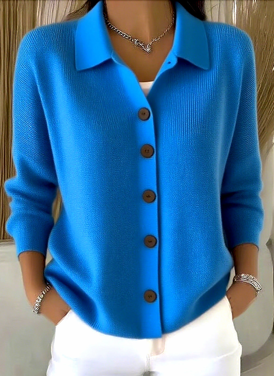 Blue cardigan with brown buttons worn by a person against a neutral background