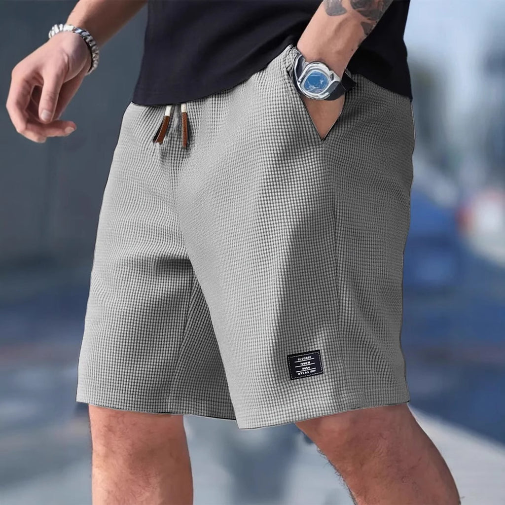 Person wearing gray checkered shorts with a blurred background