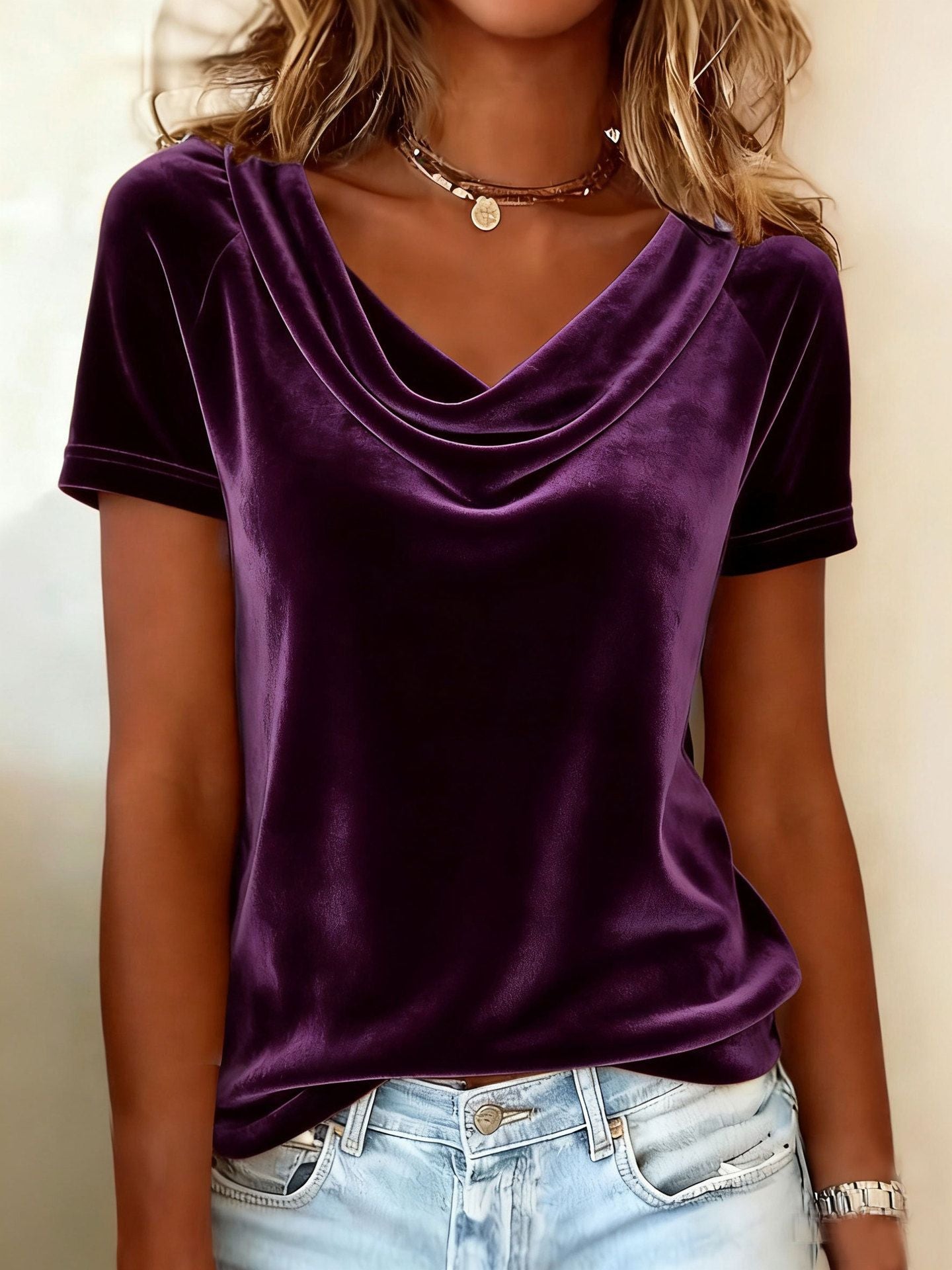 Person wearing a purple velvet top and light blue jeans against a neutral background