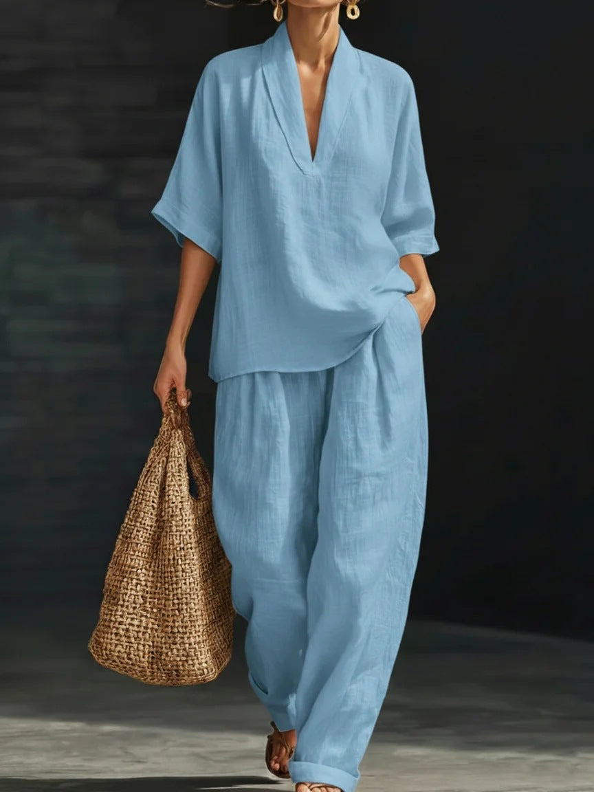 Woman in a light blue outfit holding a woven bag against a dark background