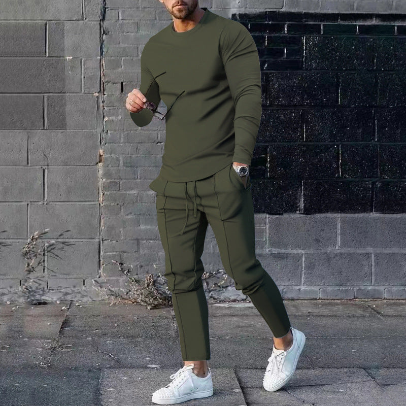 Man wearing an olive green outfit with white sneakers against a brick wall.