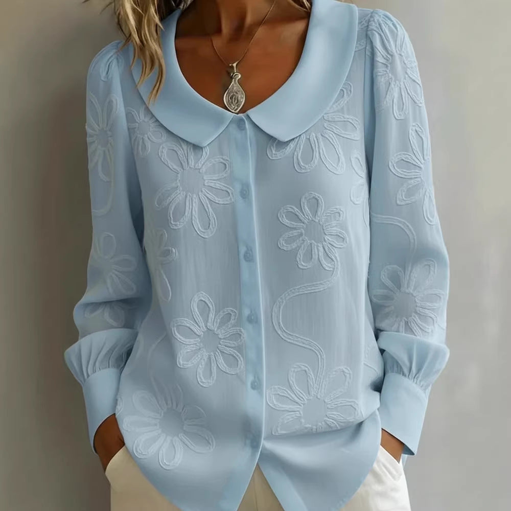 Light blue blouse with floral embroidery on a plain background