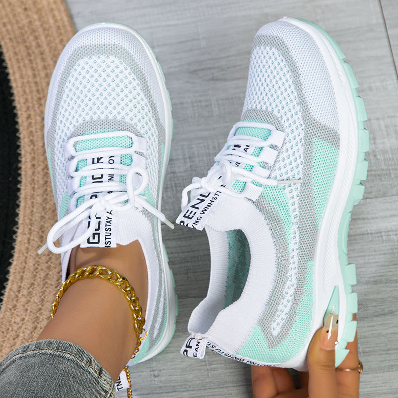 Pair of white and green sneakers on a neutral background