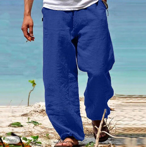 Person wearing blue pants standing on a beach with turquoise water in the background