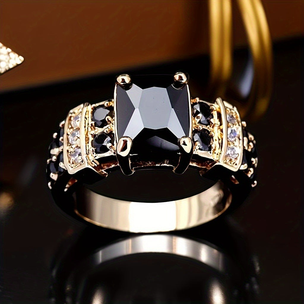 Gold ring with a black gemstone on a reflective surface
