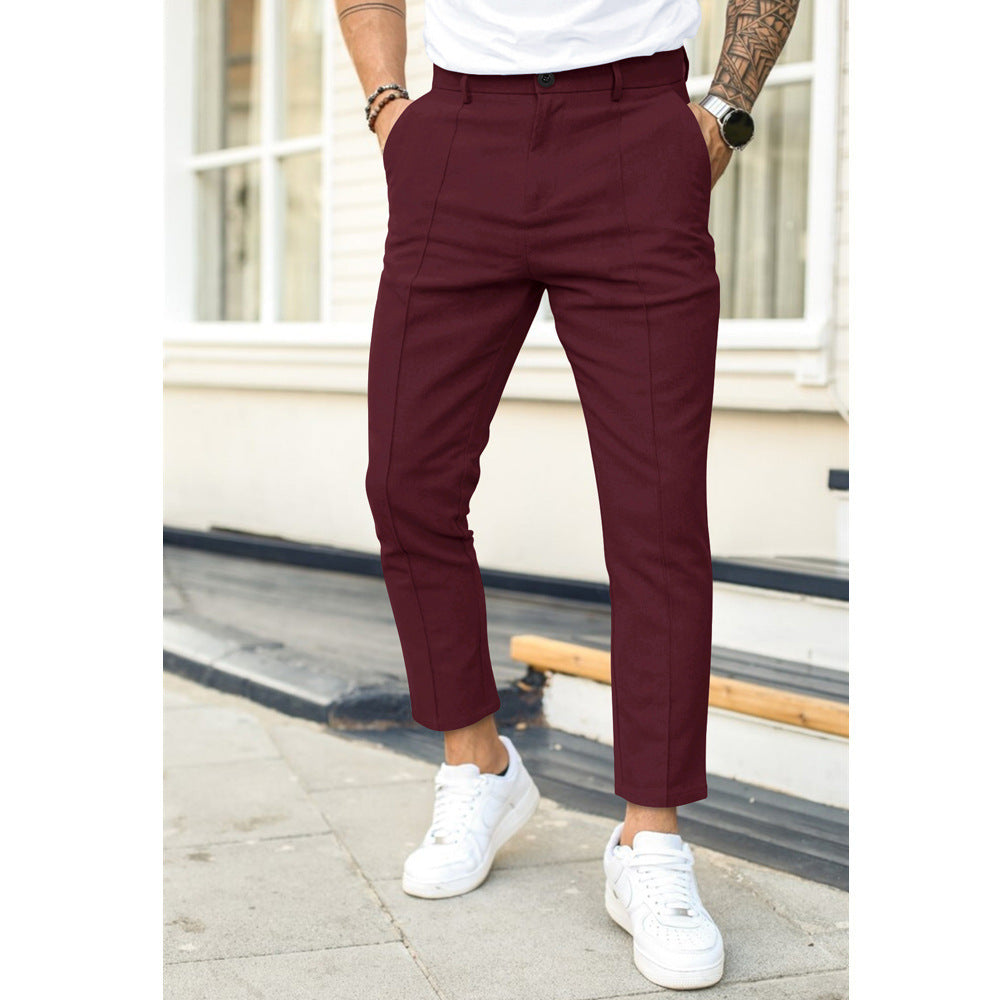 Person wearing maroon pants and white sneakers on a city street.