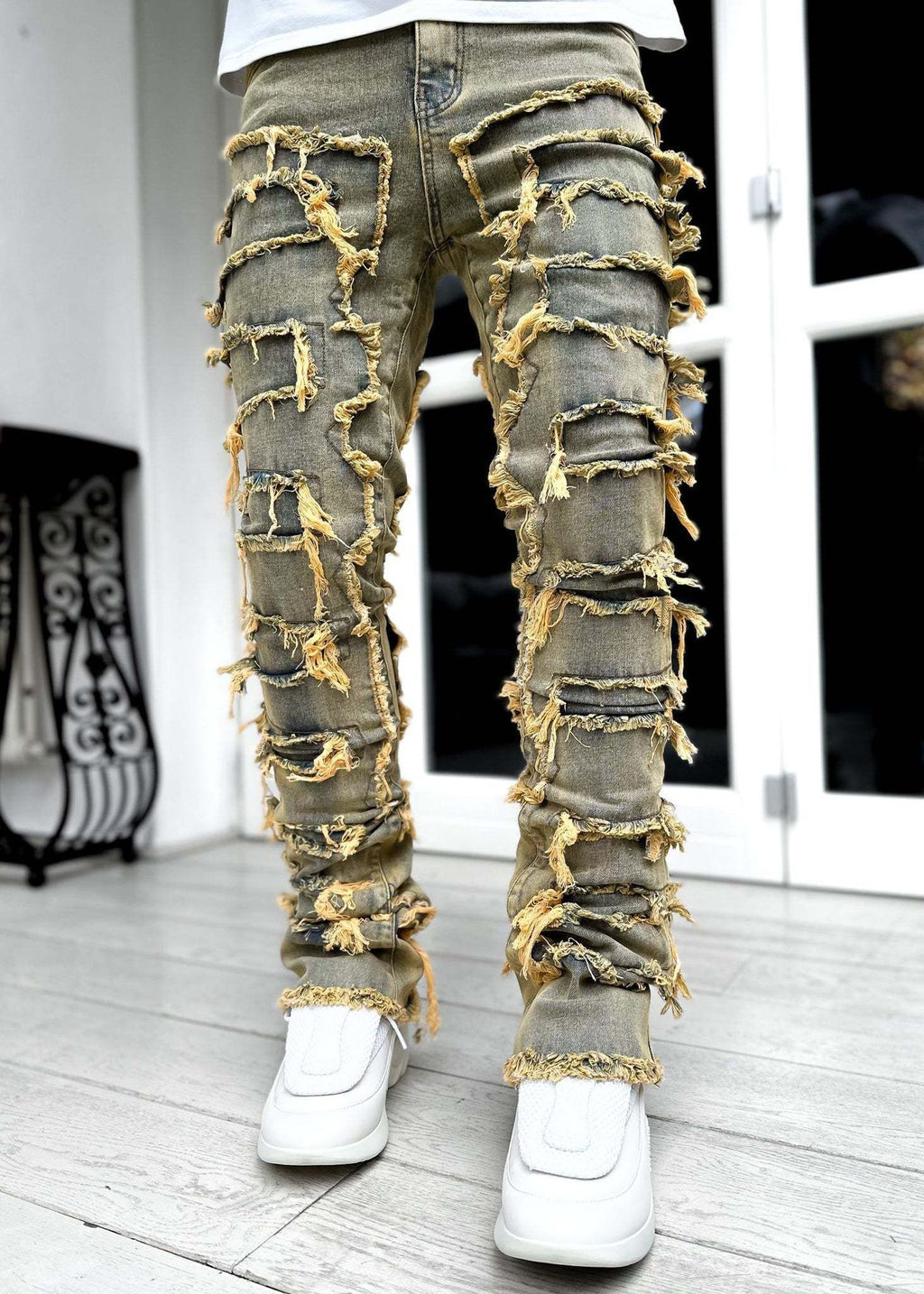 Ripped jeans with gold accents worn by a person indoors.