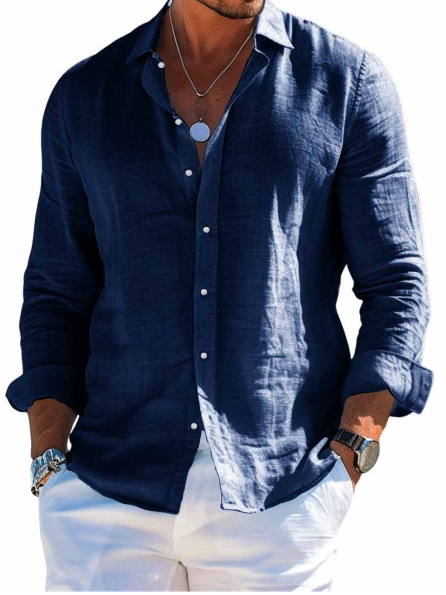 Man wearing a navy blue button-up shirt with white pants on a white background
