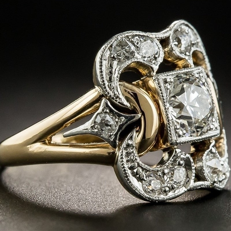Gold and silver ring with diamond accents on a dark background