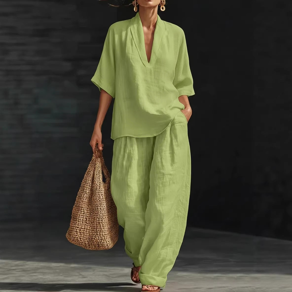 Person wearing a green outfit holding a woven bag against a dark background