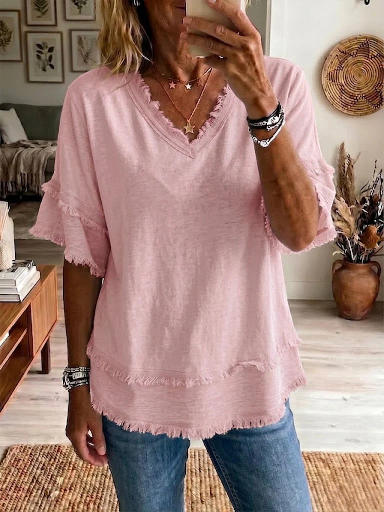 Person wearing a pink blouse with ruffled sleeves in a living room setting.