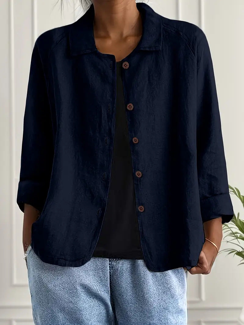 Person wearing a navy blue button-up shirt over a black top with light blue jeans indoors.