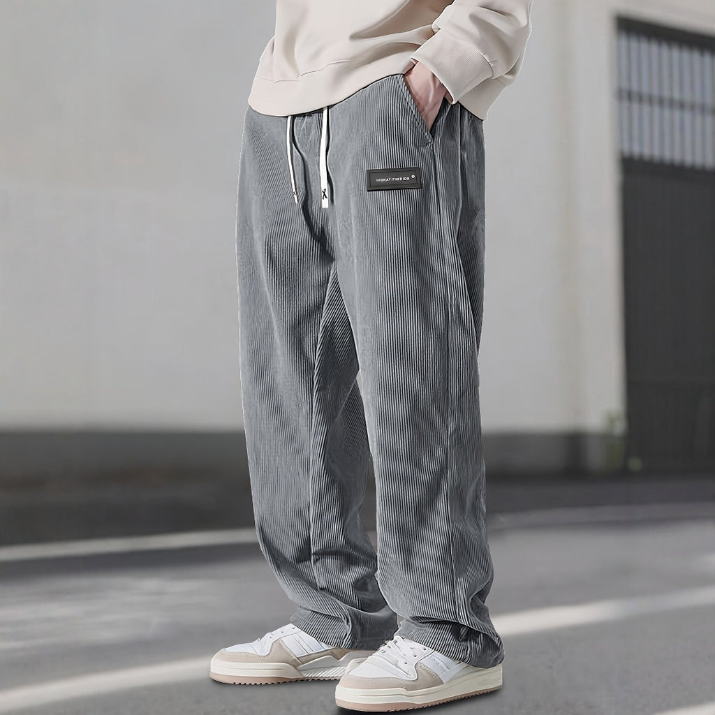 Person wearing gray striped pants with a small patch on a plain background